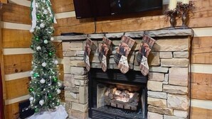 Een open haard met sokken, een kerstboom en een televisie erboven.