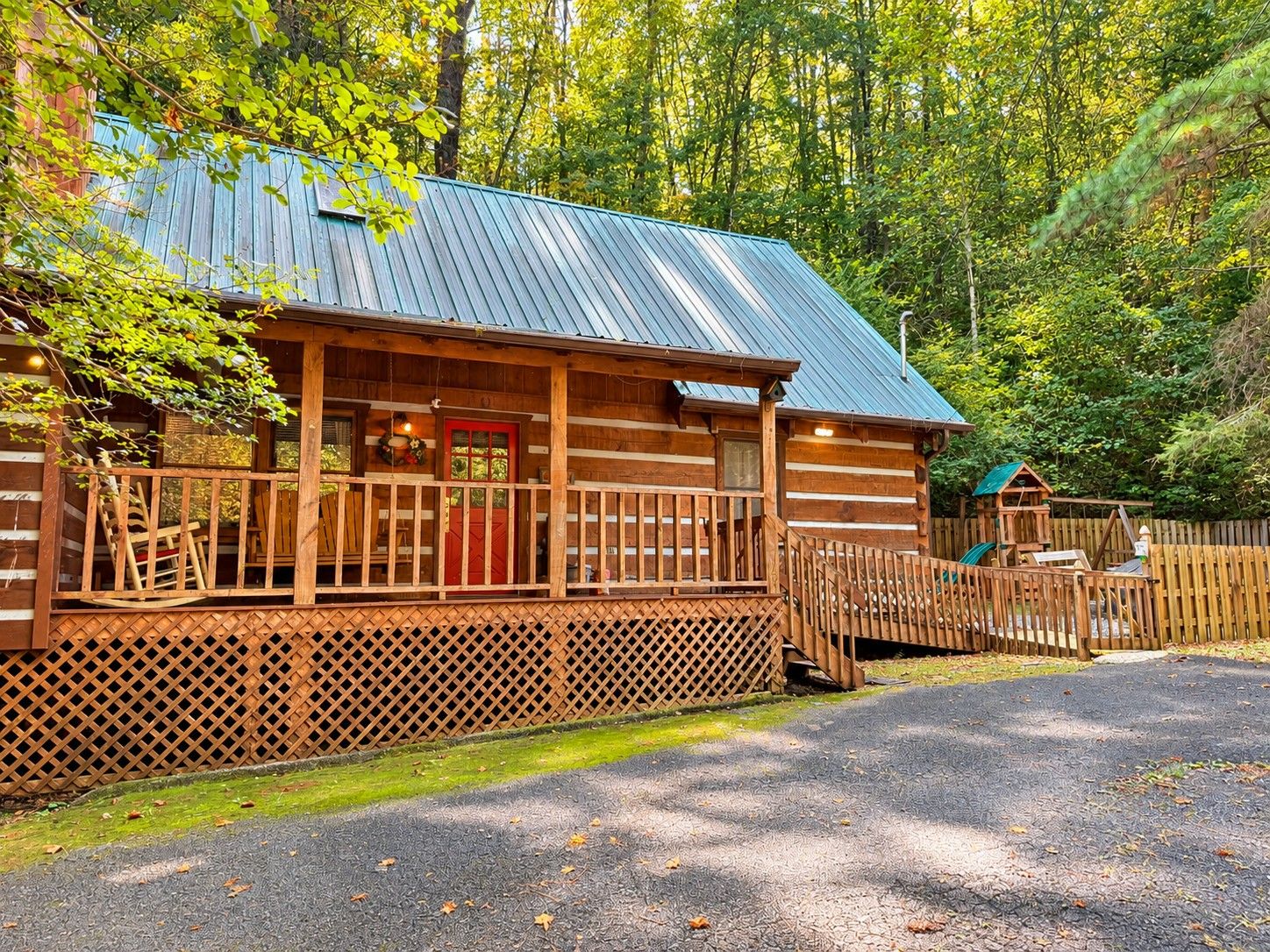 Eine Blockhütte mit Veranda, einer roten Tür und einem Metalldach.