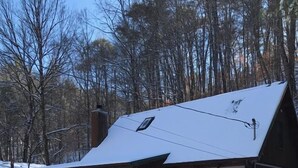 Een blokhut met een met sneeuw bedekte dak, een veranda en een trap naar de ingang.