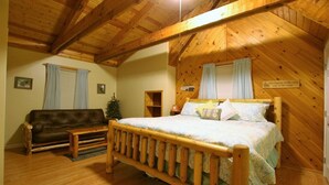 Een gezellig slaapkamer in blokhutstijl met een houten bed, een bank en een klein tafeltje.