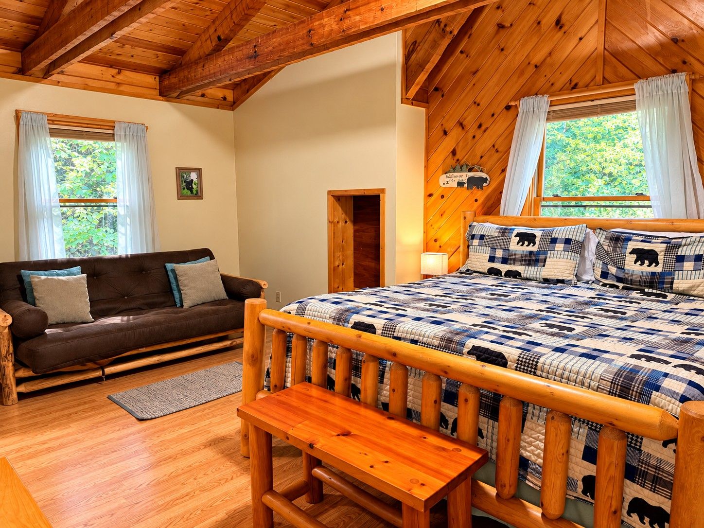 Ein gemütliches Zimmer mit einem hölzernen Bett, einem braunen Sofa und einer Bank.
