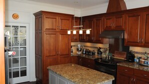 A kitchen with wooden cabinets, granite countertops, a stove, and a range hood. - Pond View Retreat: Your Ultimate Athens Getaway Minutes To Sanford Stadium (Athens)