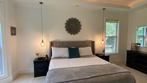 A bedroom with a large bed, two bedside tables, a ceiling fan, and a decorative wall piece. - Pond View Retreat: Your Ultimate Athens Getaway Minutes To Sanford Stadium (Athens)