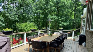 A wooden deck with a table and chairs, surrounded by potted plants and a railing. - Pond View Retreat: Your Ultimate Athens Getaway Minutes To Sanford Stadium (Athens)