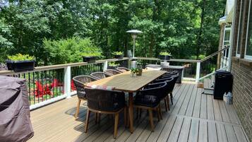 Een houten terras met een tafel en stoelen, omringd door potplanten en een balustrade.