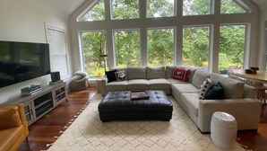 A spacious living room with a large sectional sofa, a flat-screen TV, and a ceiling fan. - Pond View Retreat: Your Ultimate Athens Getaway Minutes To Sanford Stadium (Athens)