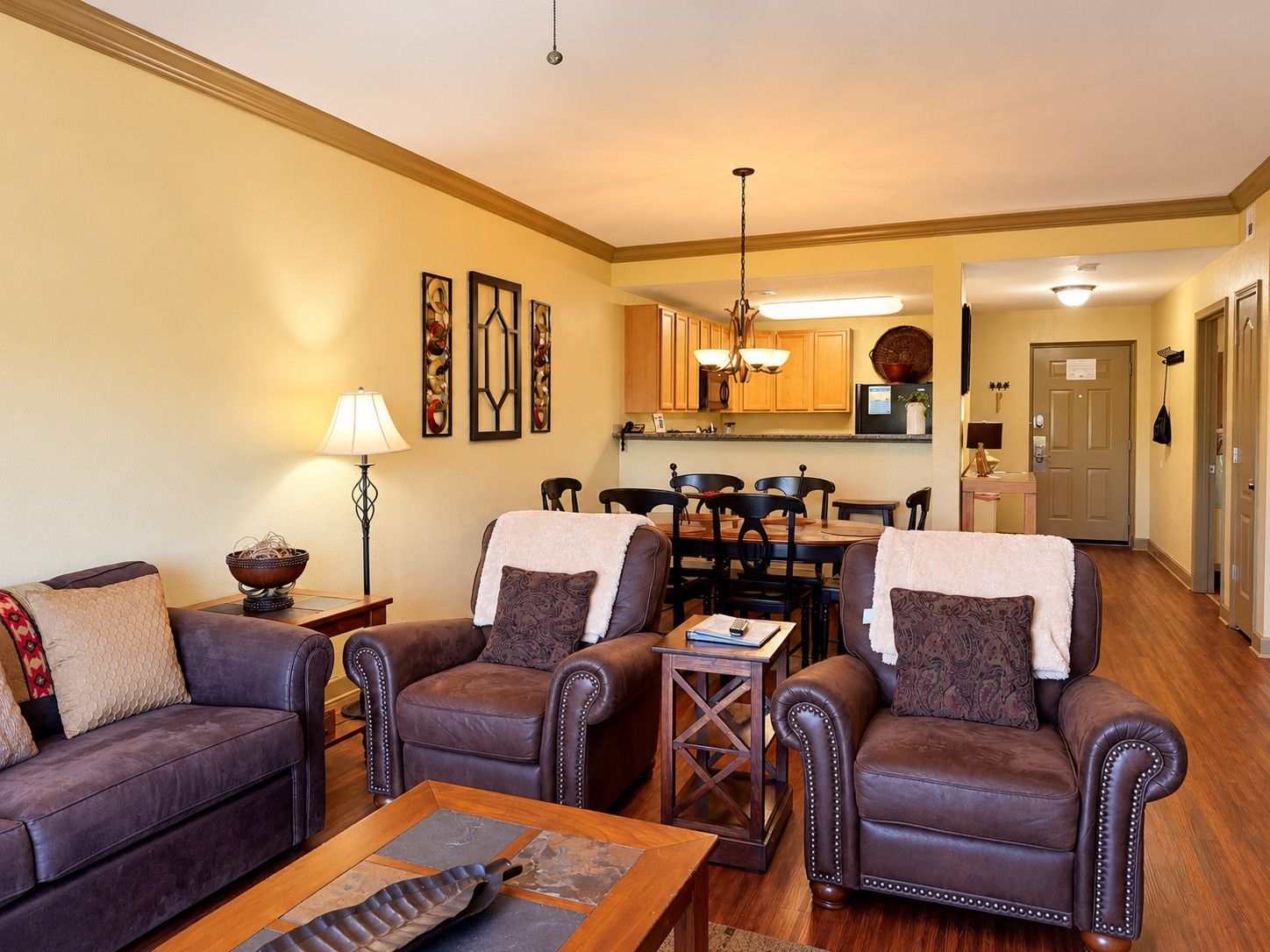 A living room with leather sofas, a coffee table, and a dining area with a wooden table and chairs.