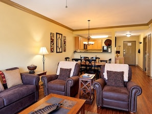 A living room with leather sofas, a coffee table, and a dining area with a wooden table and chairs.