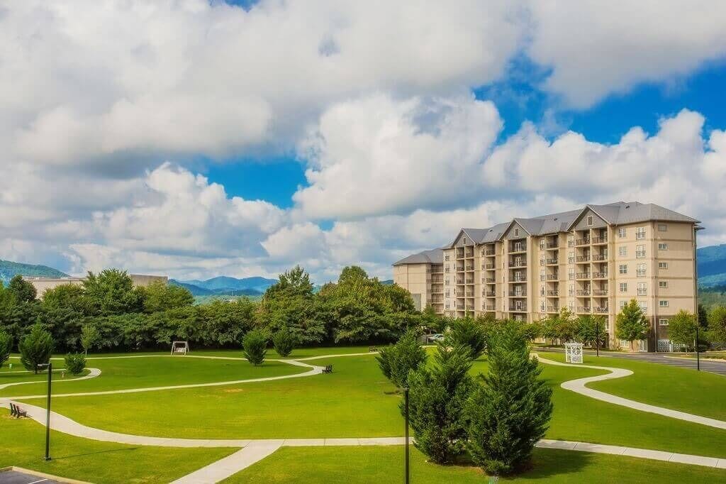 Un hotel de varios pisos con un patio central, rodeado de abundante vegetación y montañas al fondo.