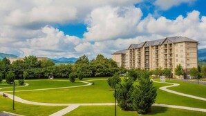 A multi-story hotel with a central courtyard, surrounded by lush greenery and mountains in the background. - Free Daily Activities - Beautiful Mountain Views - Indoor Pool (Pigeon Forge)