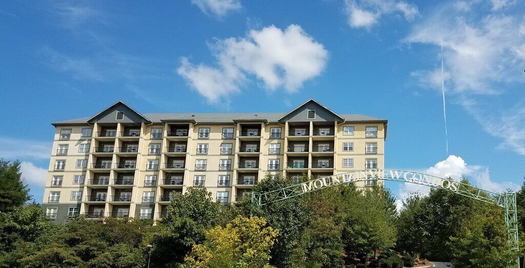 Un hotel de varios pisos con balcones, cielo despejado y un letrero que dice 'The Mountain Lakes'.
