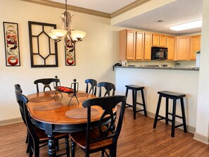 A dining area with a round table, black chairs, and a chandelier.