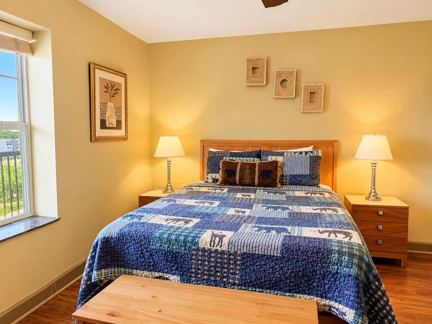 A bedroom with a bed, two bedside tables, a window, and a framed picture on the wall.