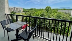 A balcony with a table and chairs, overlooking a road and greenery. - Free Daily Activities - Beautiful Mountain Views - Indoor Pool (Pigeon Forge)