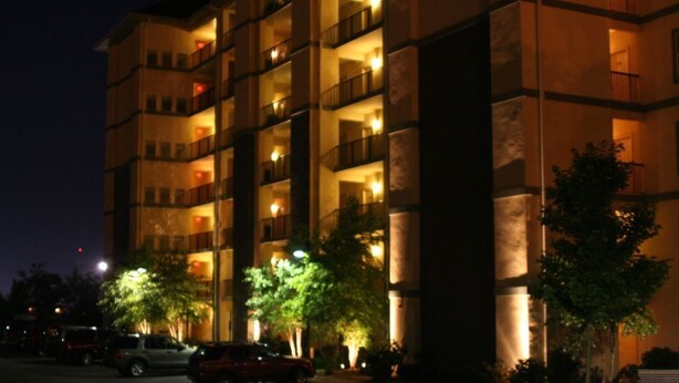 A multi-story hotel with balconies, a parking lot, and trees in front. - Free Daily Activities - Beautiful Mountain Views - Indoor Pool (Pigeon Forge)
