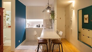 A modern kitchen with a white island, bar stools, and a hanging light fixture. - FLH Chiado Nature Apartment (Lisbon)