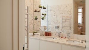 A bathroom with a marble countertop, two sinks, a mirror, and decorative plants. - FLH Chiado Nature Apartment (Lisbon)