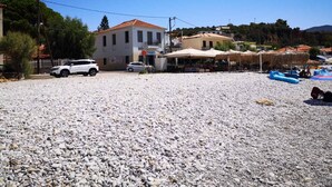 Une propriété située en bord de mer, dotée d’une zone pavée, d’un bâtiment avec un toit recouvert de tuiles rouges et d’un espace extérieur aménagé pour s’asseoir.