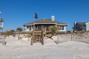 Une maison située en bord de mer, dotée d’une terrasse en bois et d’un drapeau.