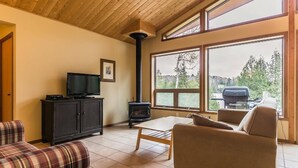 A cozy living room with a fireplace, a television, and a view of the outdoors. - Welcome to the Chalets du Lac Grenier (Chertsey)