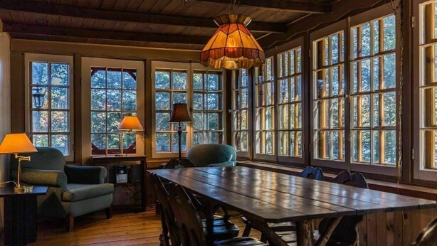 Un comedor con una gran mesa de madera, varias sillas y una lámpara colgante.