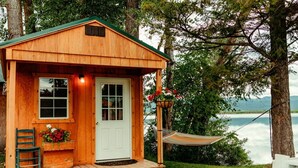 Een houten hut met een veranda, een deur, een raam, een bankje en een hangmat.