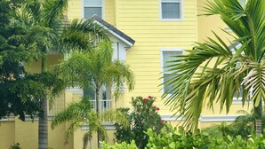 A yellow building with a gabled roof, surrounded by lush greenery and palm trees. - Paradise Lovers Dream Coronas Amarilla (Siesta Key)