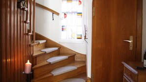 A wooden staircase with a candle, a window with stained glass, and a wooden door. - Landhaus Büttner Altenberg (Altenberg)