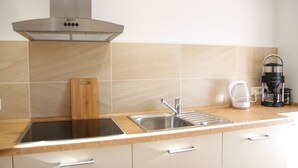 A kitchen with a stainless steel sink, a coffee maker, and a cutting board. - Landhaus Büttner Altenberg (Altenberg)
