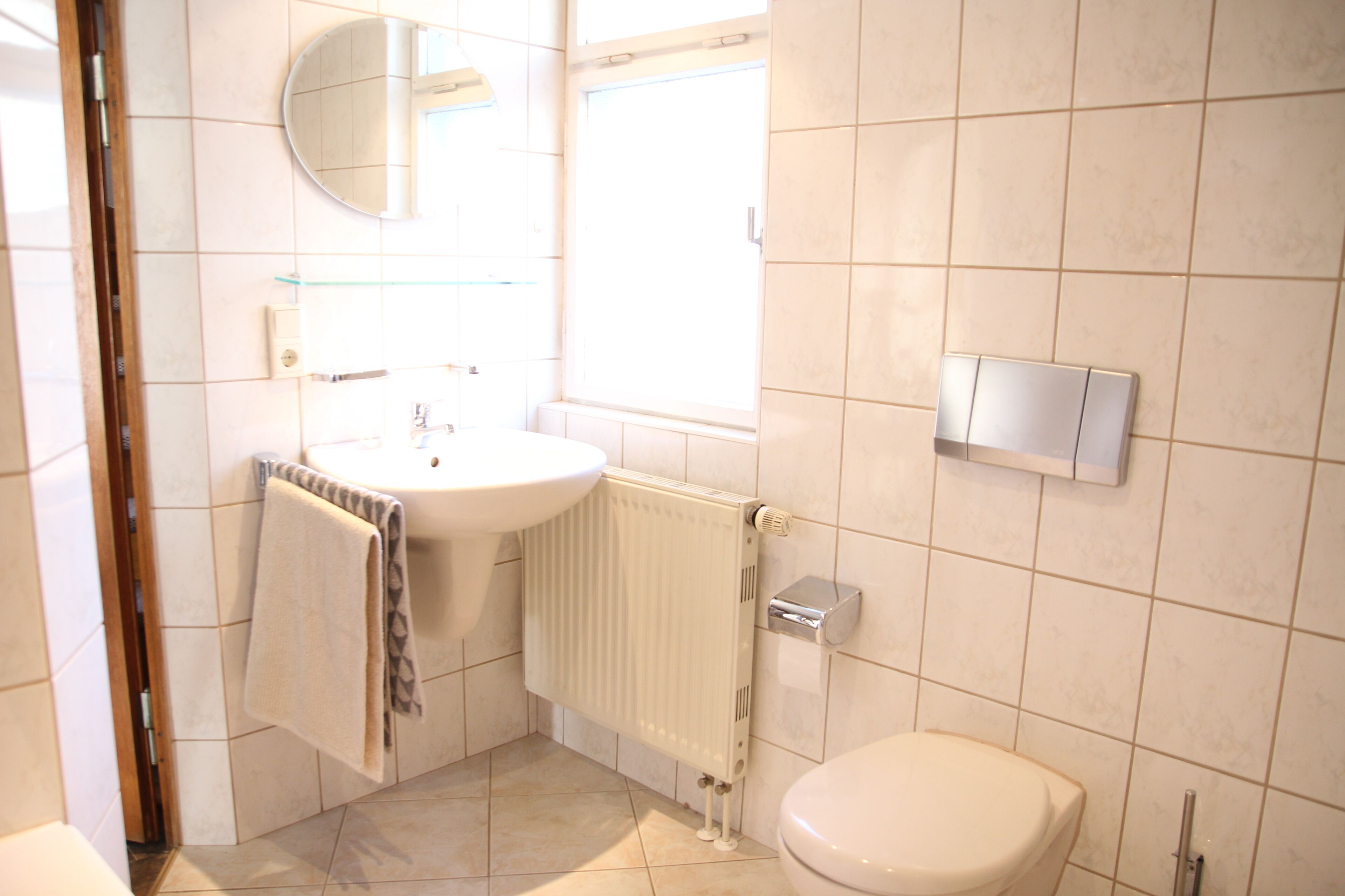 Une salle de bain équipée de toilettes, d’un lavabo, d’un miroir et d’une fenêtre.
