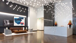 A modern reception area with a marble counter, a large abstract painting, and a hanging light fixture. - Mint House Miami - Downtown (Miami)