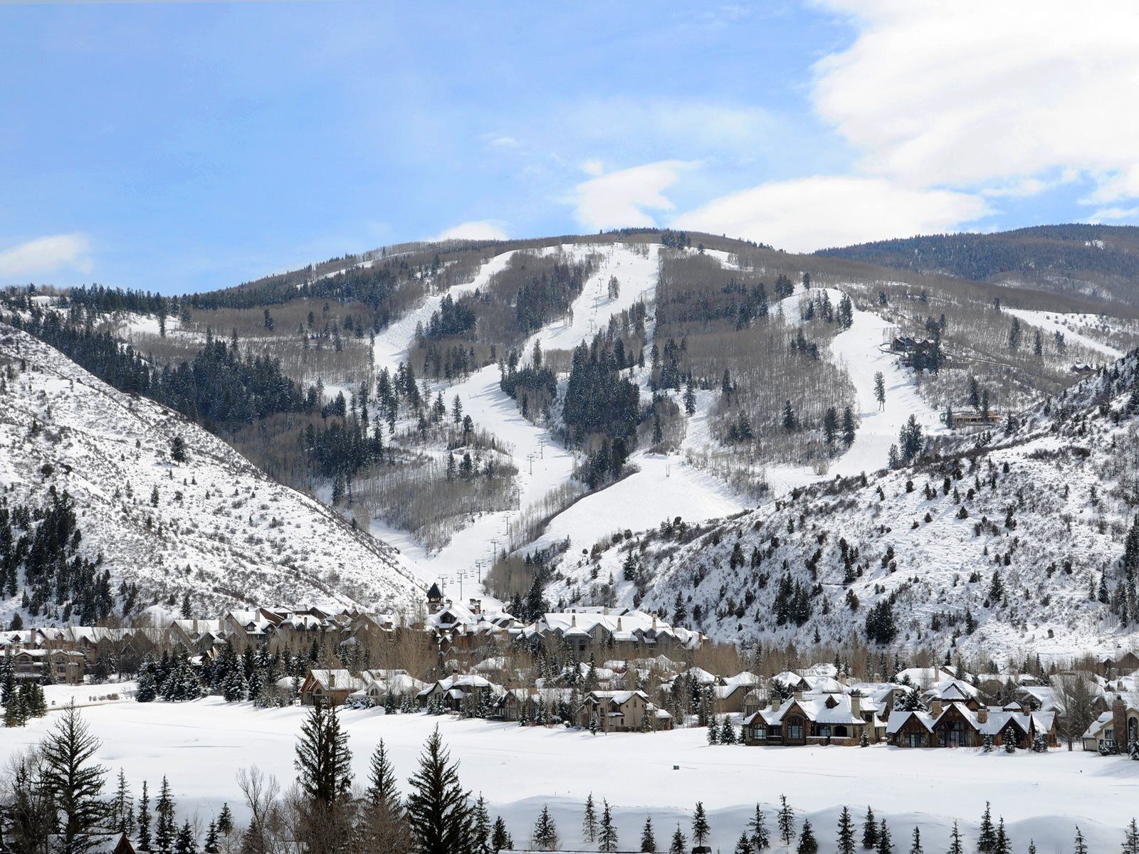 A snow-covered mountain landscape with a ski resort and lodge buildings.