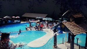 Ett poolområde med flera pooler, en vattenrutschkana och ett avskärmat sittområde.