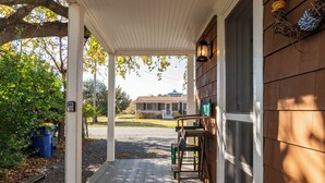 A covered porch with a bench, chairs, and a rug. - 303 Massachusetts - Adorable one bedroom cottage close to the beach! (Lewes)