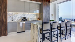 A modern kitchen with marble countertops, a built-in oven, and a bar area with bar stools. - Ritzy Pier 57 Ocean Views Ocean Views Rooftop Pool Zona Romantica (Puerto Vallarta)