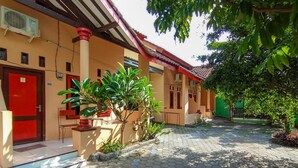 A building with a red door, hexagonal tiled walkway, and potted plants. - El Shaday Family Residence (Banyuwangi)