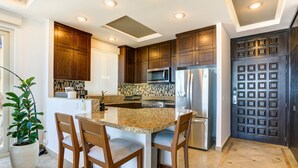 A modern kitchen with wooden cabinets, stainless steel appliances, a granite countertop, and a potted plant.
