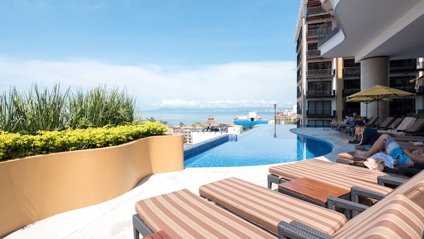 A rooftop pool area with lounge chairs and a view of the ocean.