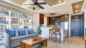 A modern living room with a gray sofa, wooden coffee table, and a dining area with a kitchen in the background.