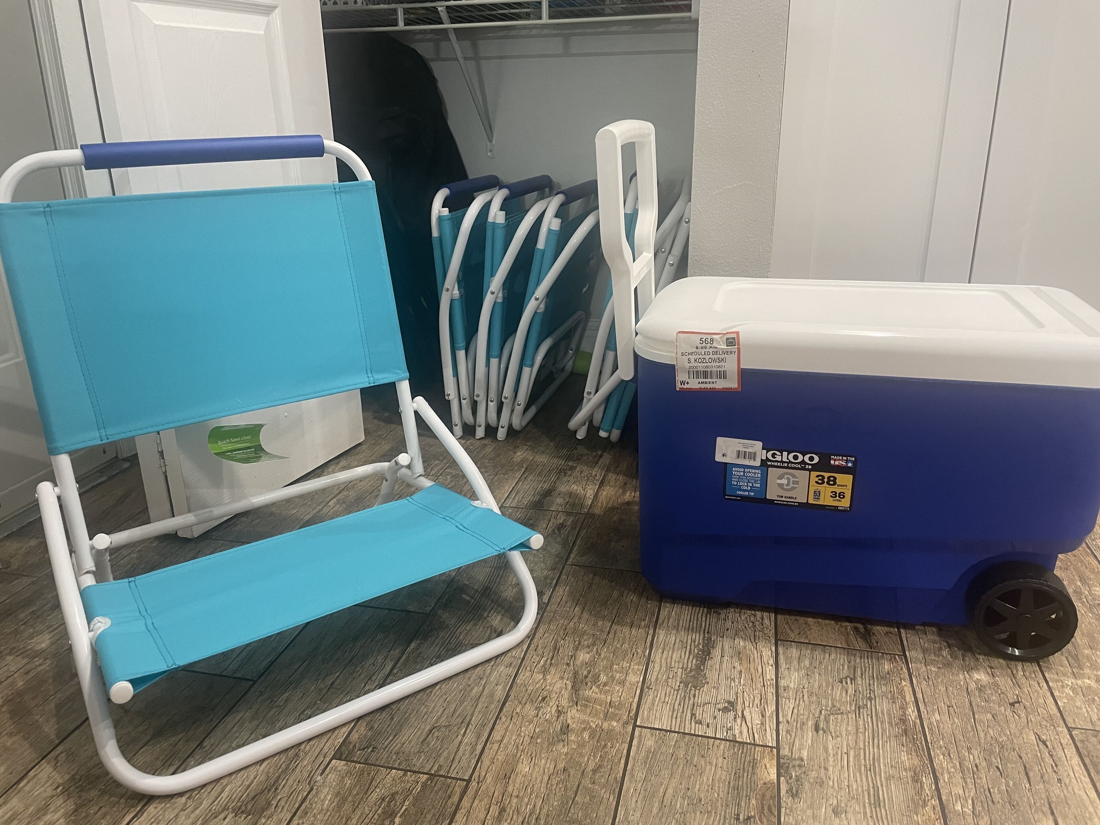A blue folding chair and a blue and white cooler with wheels.