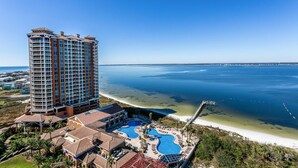 Un hôtel de grande hauteur doté de nombreux balcons, d’un espace piscine donnant sur la plage et offrant une vue sur l’océan.