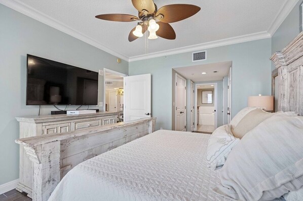 A bedroom with a large bed, a TV mounted on a dresser, and a ceiling fan. - P2-1509 2B Elite Rated Island View @ Portofino! (Pensacola Beach)