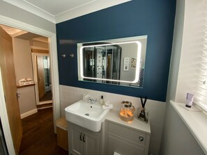 A bathroom with a white sink, a mirror with LED lights, a towel rack, and a small cabinet. - Cotswolds Blenheim Burford Oxford Bibury Minster Mill Diddly Farmers Dog Soho  (Minster Lovell)