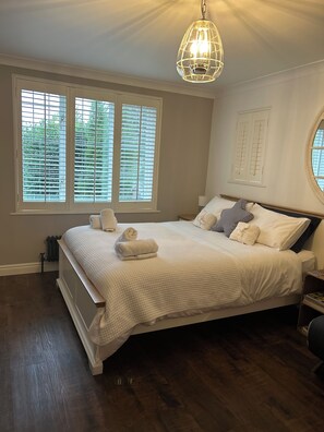 A bedroom with a large bed, white bedding, a round window, and a ceiling light fixture. - Cotswolds Blenheim Burford Oxford Bibury Minster Mill Diddly Farmers Dog Soho  (Minster Lovell)