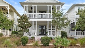 A two-story white house with a front porch, columns, and a black front door.