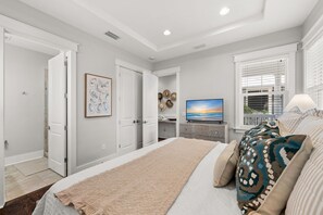 A bedroom with a bed, a TV, and a window with blinds.