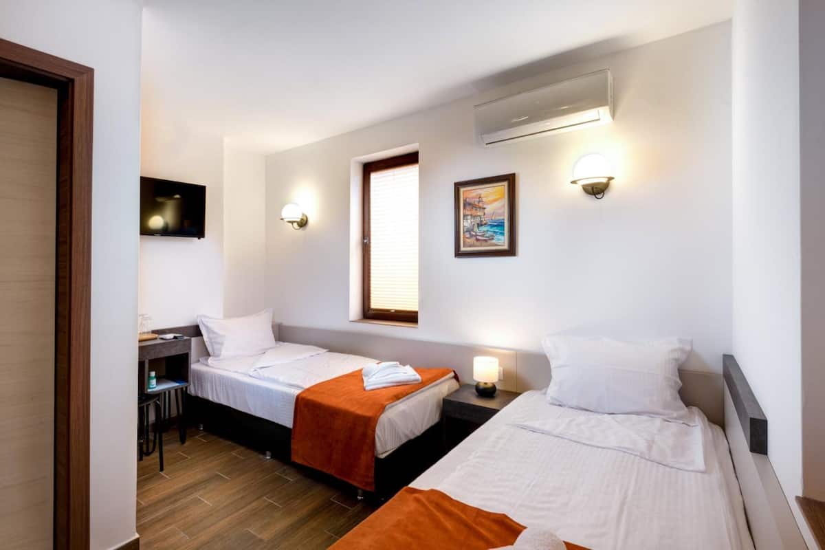 A hotel room with two beds, a desk, and a small table.