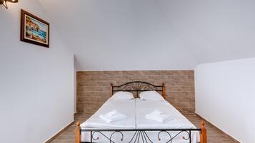 Una cama bien hecha con sábanas y toallas blancas, un cabecero de madera y un cuadro en la pared.