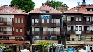 Un hotel frente al agua con varios balcones, un muelle con barcos y un letrero que dice 'PANORAMA BLDG FAMILY HOTEL'.