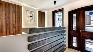 Un área de recepción moderna con un panel de madera, una obra de arte geométrica y un mostrador de recepción de tonos oscuros.